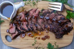 Sliced Godfather steak fanned on a board with pan jus